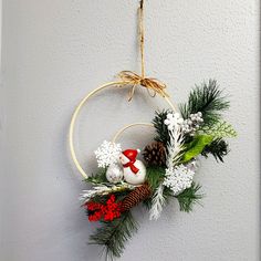 a christmas wreath hanging on the wall with pine cones, berries and other decorations around it