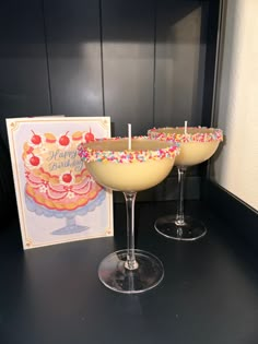 two champagne glasses with sprinkles on them next to a birthday card