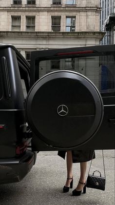 a woman is standing in front of a mercedes suv with the door open and her hand on the wheel