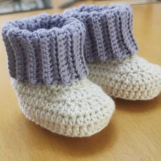 a pair of crocheted baby booties sitting on top of a wooden table