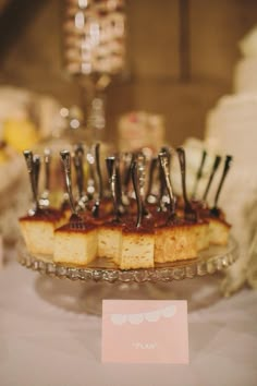 there are many small pieces of cake on the plate with forks in it and a place card next to them