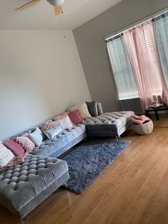 a living room filled with furniture and a large window covered in pink draping