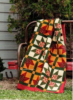 a quilted blanket sitting on top of a metal bench in front of a house