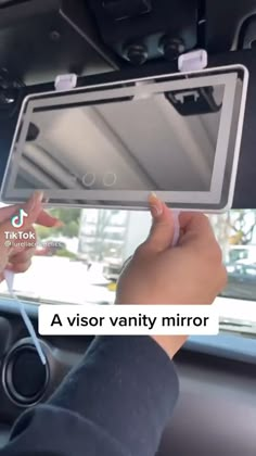 a person holding up an electronic device in their hand with the text, a visor vanity mirror