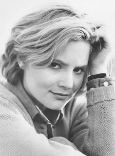 a black and white photo of a woman with her hand on her head, wearing a sweater