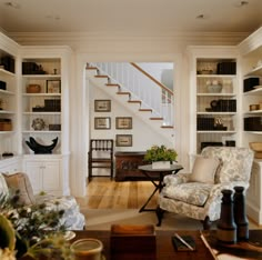 a living room filled with furniture and bookshelves next to a stair case in a home