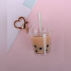 a drink in a plastic cup with two straws and a heart shaped keychain