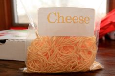 a bag of noodles sitting on top of a wooden table next to a box with a sign that says cheese