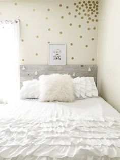 a white bed topped with pillows next to a window covered in polka dot wallpaper