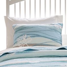 a bed with blue and white comforter, pillows and pillow cases on top of it