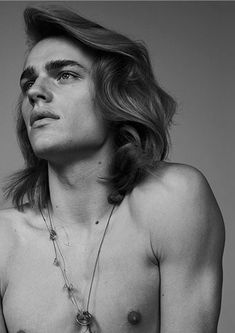 a shirtless man with long hair and no shirt is posing for a black and white photo