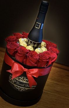 a bottle of wine in a black box with red roses and chocolates on it