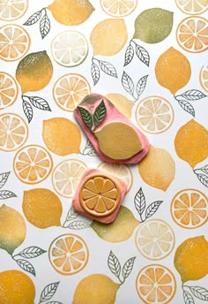 two oranges are sitting on top of a tablecloth with lemons and leaves