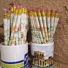 there are many pencils in the cup on the shelf next to each other,