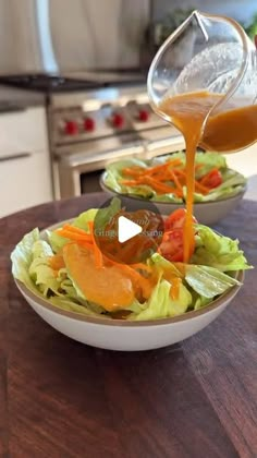 a person pouring dressing into a salad in a bowl with lettuce and carrots