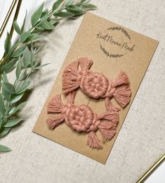 two pink crocheted bows on top of a card next to some green leaves