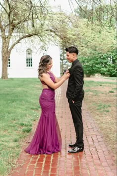 a man and woman in formal wear standing next to each other on a brick walkway