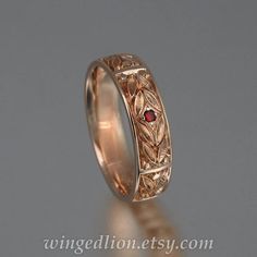 a wedding ring with a red stone in the center and an intricate design on it