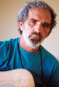 a man with grey hair and beard holding an acoustic guitar