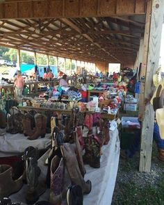 an open air market with lots of bags and purses on the tables in front of it