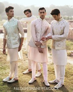 three men standing next to each other in formal wear and tuxedos, all looking at the same person's hand