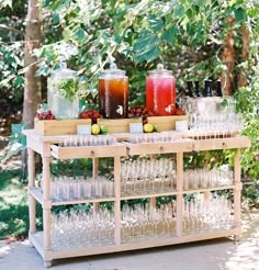 an outdoor bar with glasses, lemons and drinks on the table in front of some trees