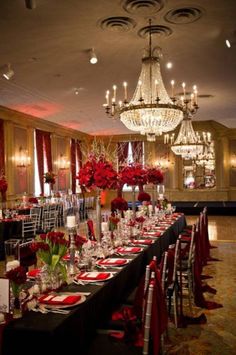 a long table is set up with red flowers and place settings for an elegant dinner