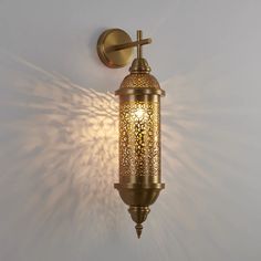 a wall light that is on the side of a white wall with sunlight coming through it