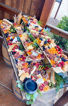 a table filled with lots of different types of food on top of wooden barrel racks