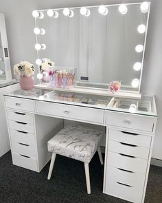 a white vanity with lighted mirror and stool