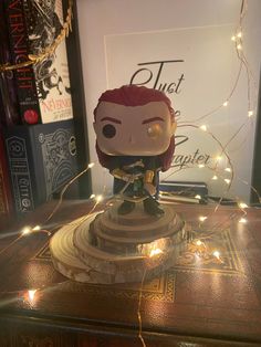 a figurine is sitting on top of a table with some lights around it