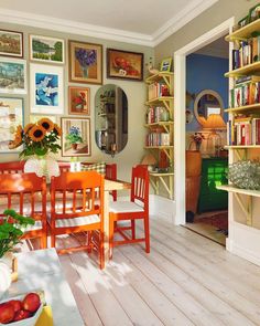 a dining room table and chairs in front of bookshelves with pictures on the wall