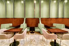 the interior of a restaurant with green walls and brown leather booths, beige upholstered chairs and wooden tables