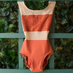 an orange and white swimsuit hanging on a green fence