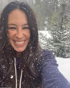 a woman is taking a selfie with snow falling on her face and trees in the background