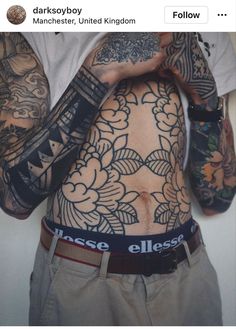 a man with many tattoos on his body and hands behind his back is holding something in front of him