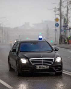 a car driving down the road in the rain with its lights on and flashing blue