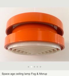 an orange lamp hanging from the ceiling in front of a white wall with text that reads space age ceiling lamp fog & morup