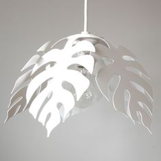 a white light hanging from a ceiling with a leaf design on it's side