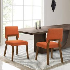 two orange chairs sitting in front of a wooden table