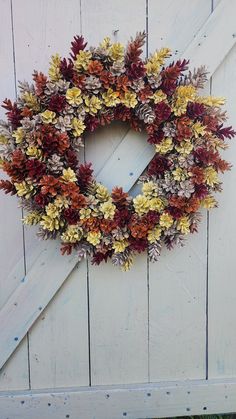 a wreath is hanging on the side of a white door with red and yellow flowers