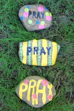 two painted rocks sitting in the grass with words pray, pray and pray written on them