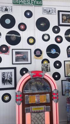 an old fashioned jukebox surrounded by records on the wall and framed with elvis presley memorabilia