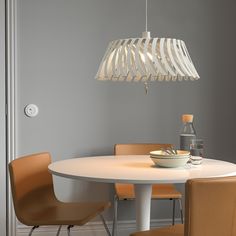 a white table with some chairs and a bowl on it in front of a gray wall