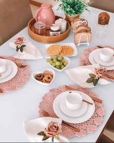 a white table topped with plates and bowls filled with food next to a pink vase