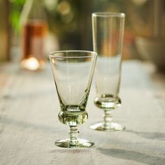 two glass goblets sitting on top of a white table cloth covered tablecloth