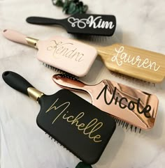 three personalized hair brushes sitting on top of a white table with gold trimmings