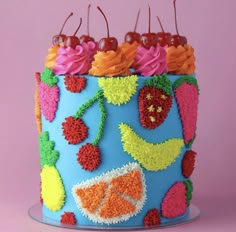 a blue cake decorated with fruit and cherries