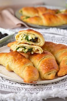 several croissants stacked on top of each other on a white plate next to blueberries