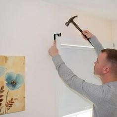 a man holding a hammer up to the ceiling